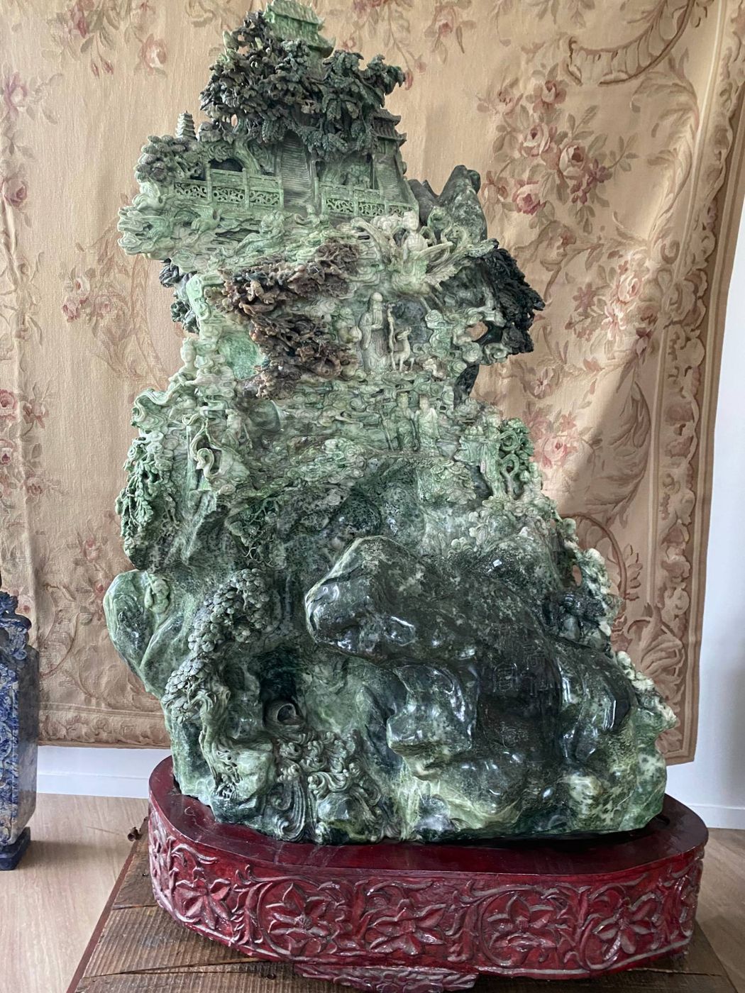 Grande sculpture chinoise en pierre dure verte : montagne sculptée de pavillons, d'arbres et de personnages, sur un socle en bois sculpté